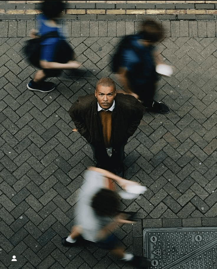 A focused person standing still as a blurred crowd rushes past
